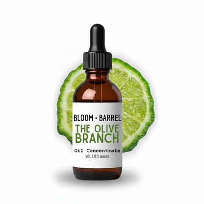 Bottle of 'The Olive Branch' oil concentrate by Bloom + Barrel on a white background with an olive slice.