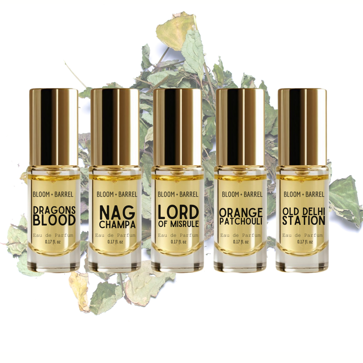 Five perfume bottles with gold caps and labels on a white background with green leaves.