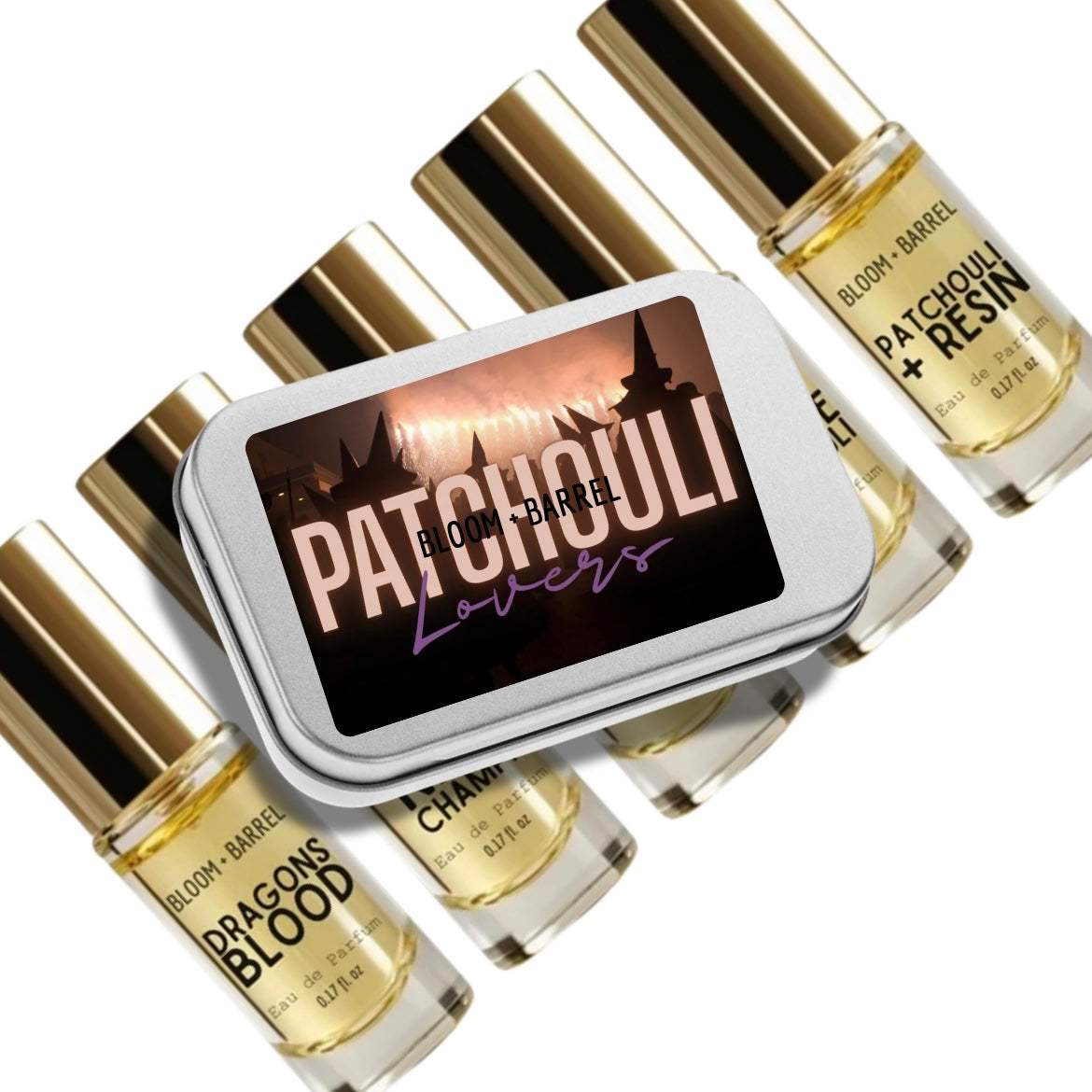 A silver rectangular tin labeled 'PATCHOULI Lovers' surrounded by several small glass perfume bottles with gold caps. The bottles are labeled with scents including 'BLOOM + BARREL', 'DRAGONS BLOOD', and 'CHAMPagne'.