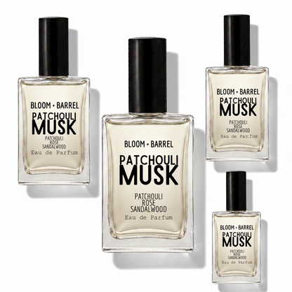 Four clear glass perfume bottles with black caps arranged on a white background. The center bottle is largest, with three smaller identical bottles around it.