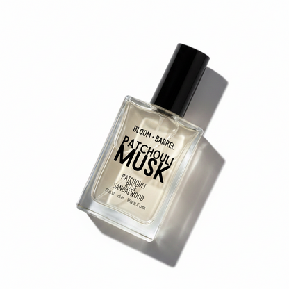 Patchouli Musk Eau de Parfum by Bloom Barrel, in a clear glass bottle with a black cap, showing a light beige liquid inside, on a solid white background.