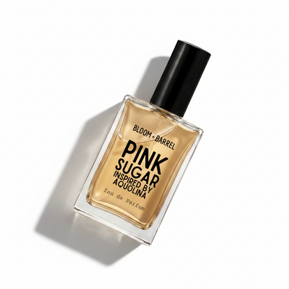 A rectangular glass perfume bottle with a black cap, filled with amber-colored liquid. The label reads 'BLOOM • BARREL PINK SUGAR INSPIRED BY AQUOLINA Eau de Parfum' in black text, set against a plain white background.