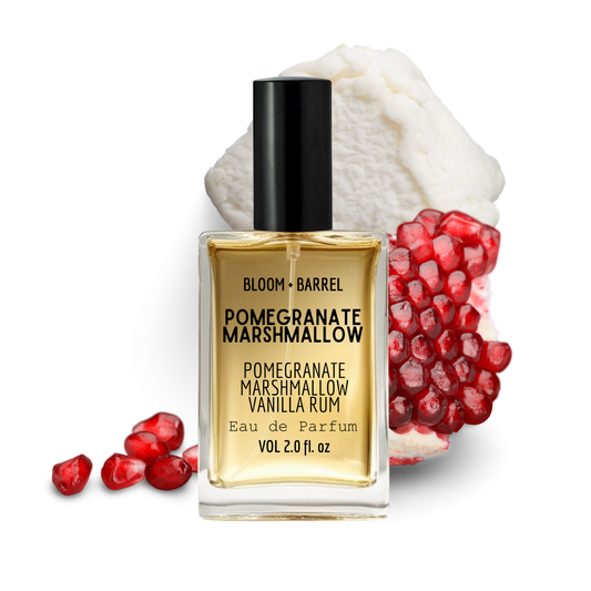 Bottle of Bloom & Barrel Pomegranate Marshmallow Vanilla Rum Eau de Parfum with pomegranate fruits on a white background
