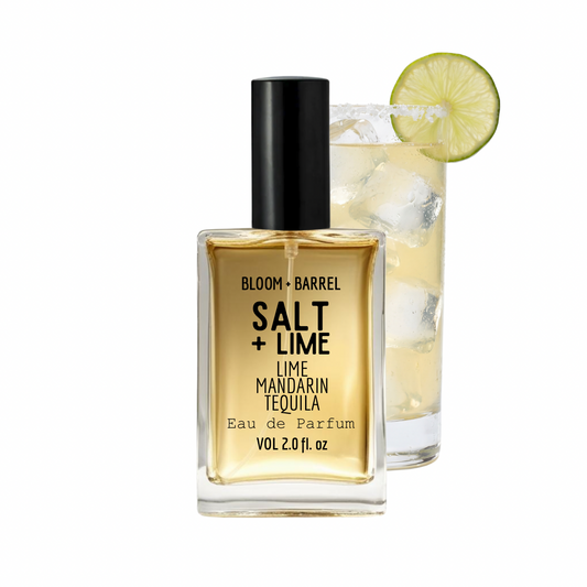 Bottle of Bloom & Barrel Salt + Lime perfume next to a glass with lime and ice.