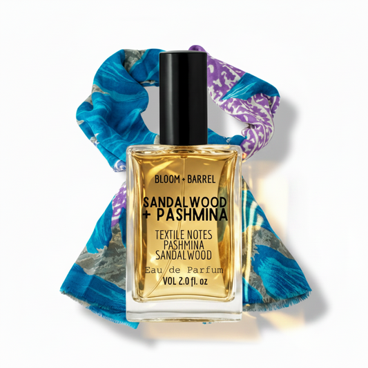 Perfume bottle labeled 'Sandalwood + Pashmina' with a colorful scarf in the background
