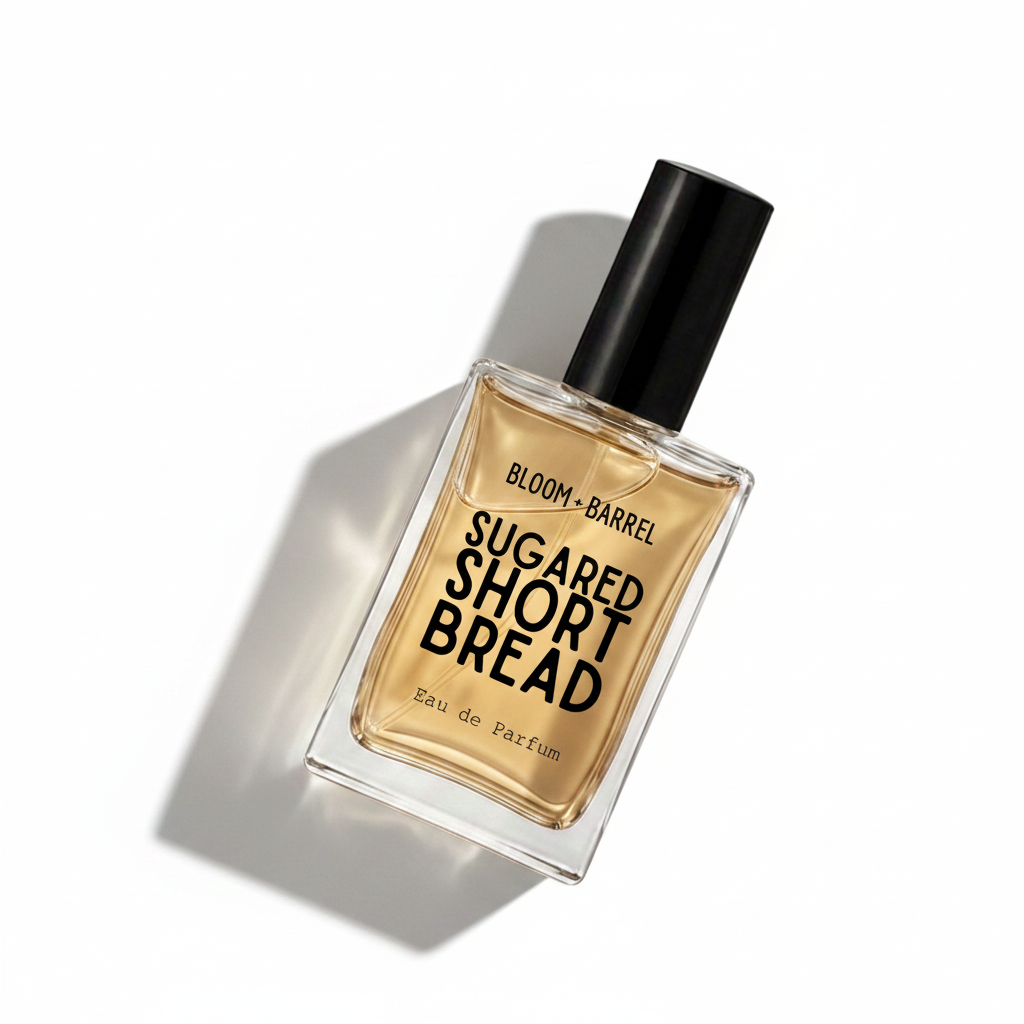 A rectangular glass perfume bottle filled with amber-colored fragrance liquid, featuring a black cylindrical cap and bold black text on the front reading 'BLOOM • BARREL' and 'SUGARED SHORT BREAD', with 'Eau de Parfum' near the bottom, set against a plain white background.