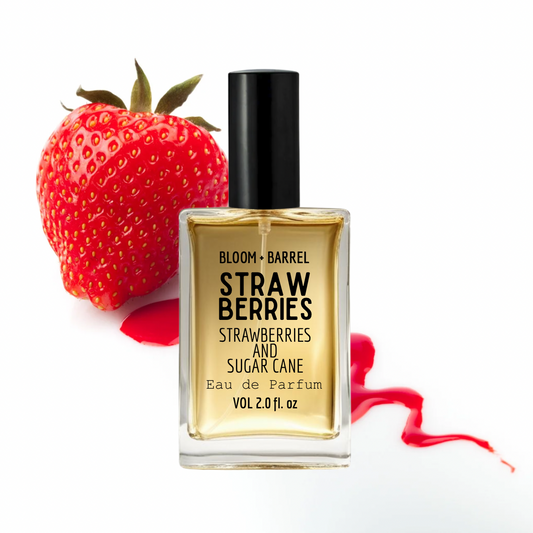 Bottle of Bloom & Barrel 'Strawberries and Sugar Cane' perfume next to a strawberry on a white background
