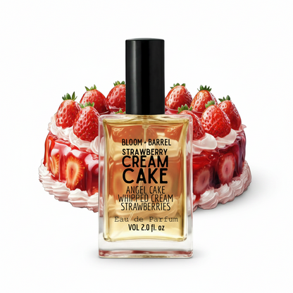 A perfume bottle labeled 'BLOOM + BARREL STRAWBERRY CREAM CAKE' stands in front of a strawberry cream cake on a plain white background.