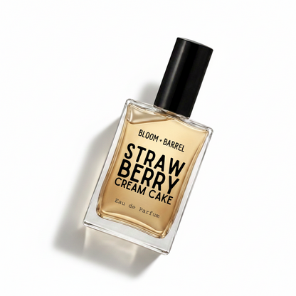 A rectangular glass perfume bottle with a black cap, filled with amber-colored fragrance liquid. The front label reads 'BLOOM • BARREL' and 'STRAWBERRY CREAM CAKE' in bold black text, with 'Eau de Parfum' near the bottom, on a plain white background.