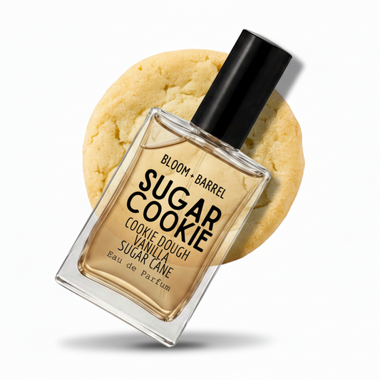 A bottle of Bloom + Barrel Sugar Cookie Eau de Parfum centered in front of a large sugar cookie graphic on a white background.