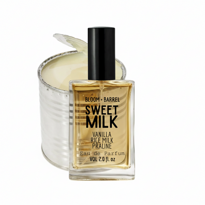 Bloom + Barrel Sweet Milk Eau de Parfum bottle in front of a silver tin candle with a wick, on a white background.
