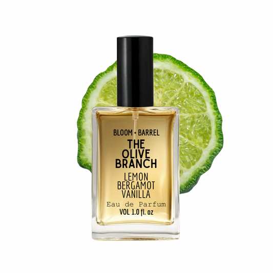 Perfume bottle labeled 'The Olive Branch' with lime slices on a white background