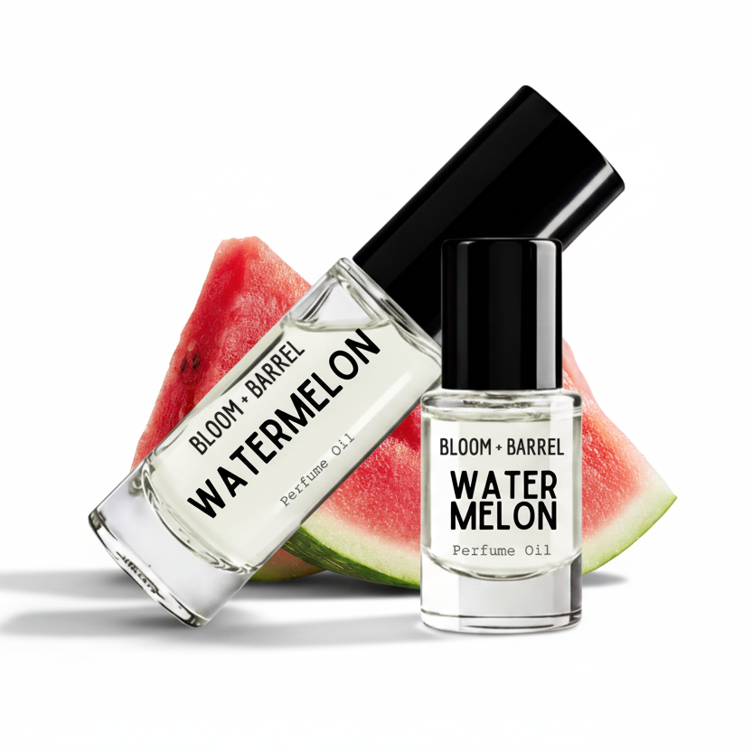 Two clear glass perfume oil bottles with black caps labeled BLOOM + BARREL WATERMelON, shown in front of watermelon slices on a white background.