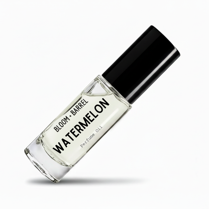 A clear glass perfume oil bottle labeled 'BLOOM • BARREL WATERMELON Perfume Oil' with a black cap, shown on a white background with a soft shadow.