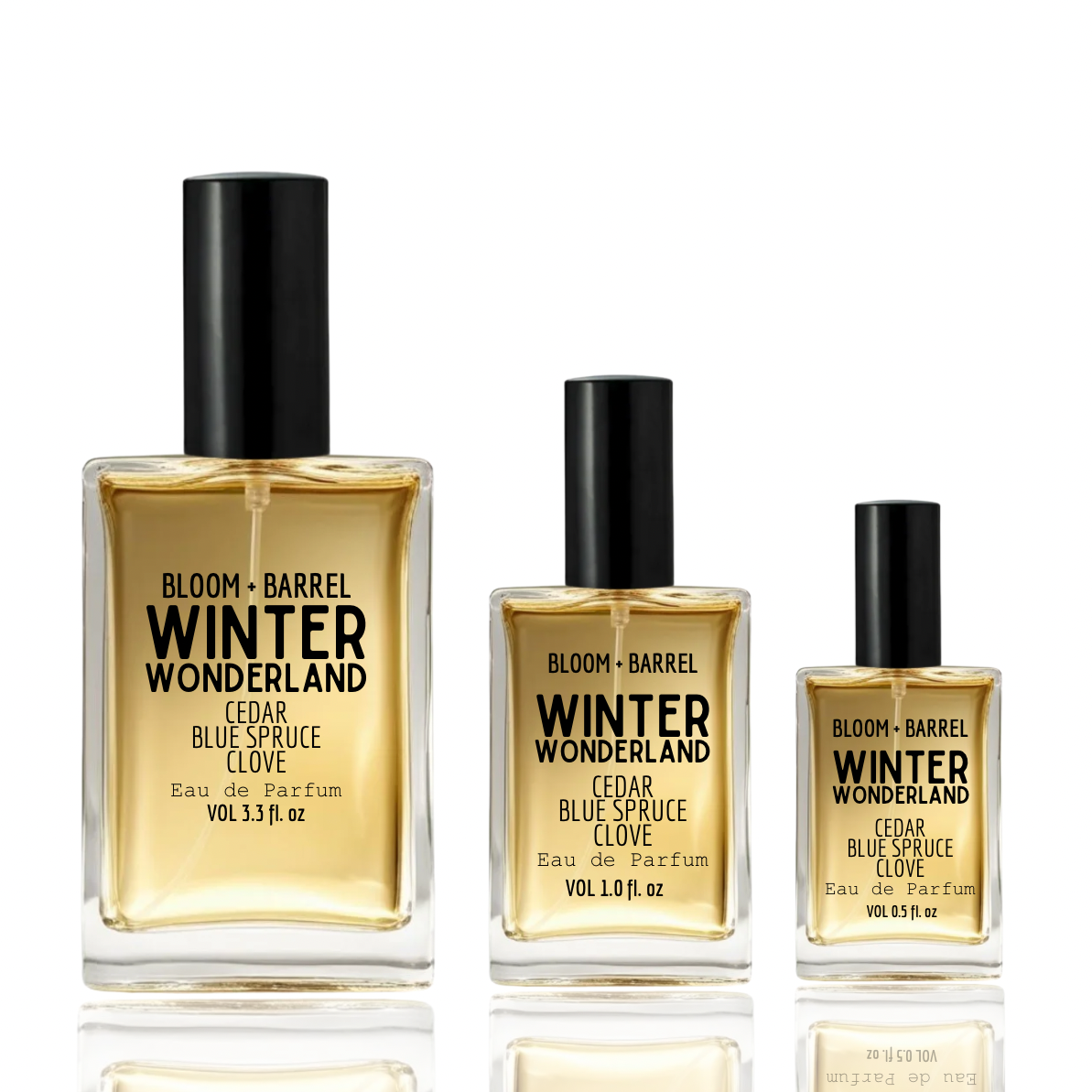 Three Bloom Barrel Winter Wonderland Eau de Parfum bottles in different sizes with black caps, filled with amber-colored liquid, on a white background with reflections.