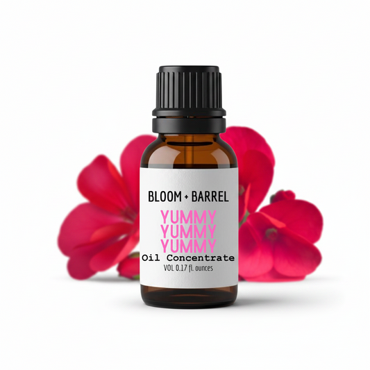 Bottle of Bloom & Barrel Yummy Yummy Oil Concentrate with red flowers in the background